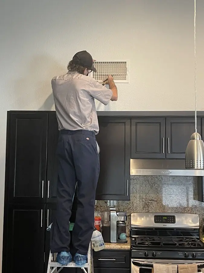 Technician inspecting an air vent during HVAC service in La Mesa